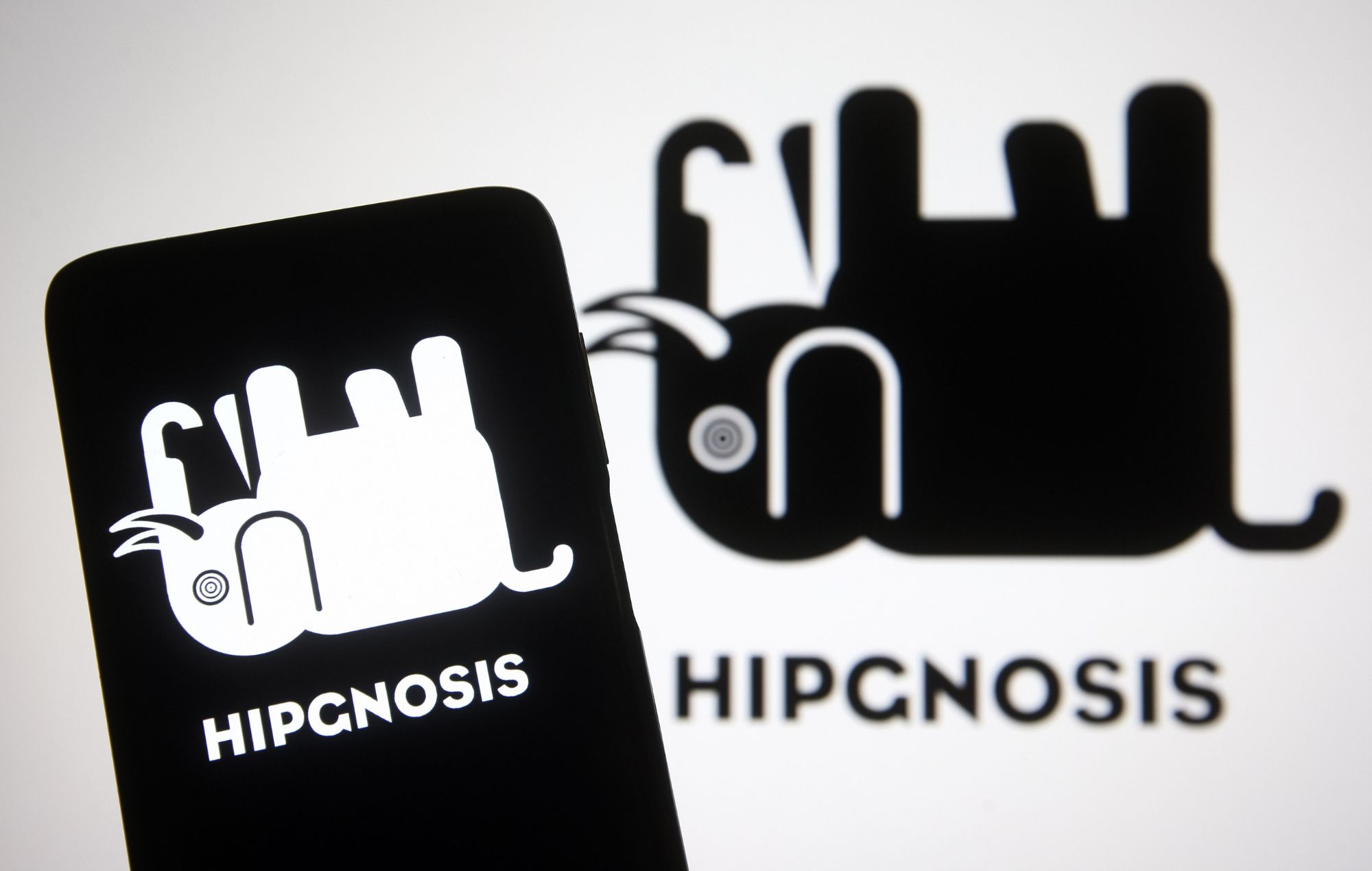 Le logo Hipgnosis Songs Fund est visible sur un smartphone et un écran d'ordinateur.