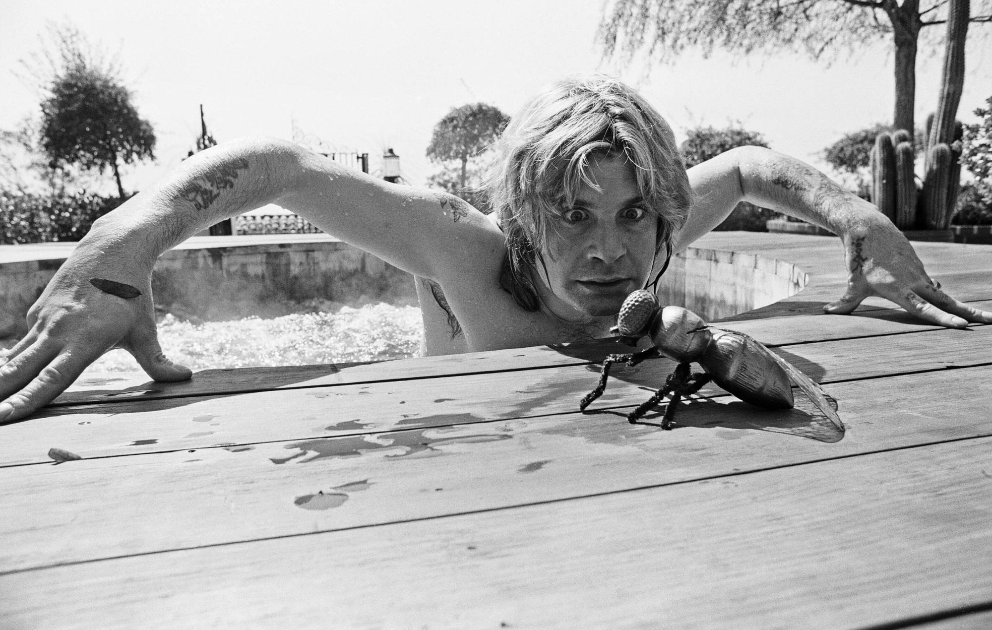 Ozzy Osbourne photographié dans son bain à remous en plein air dans le jardin de sa maison de luxe à Goldwater Canyon, Beverly Hills, Californie, avec une mouche géante en caoutchouc.  28 avril 1982. (Photo d'Eddie Sanderson/Getty Images).