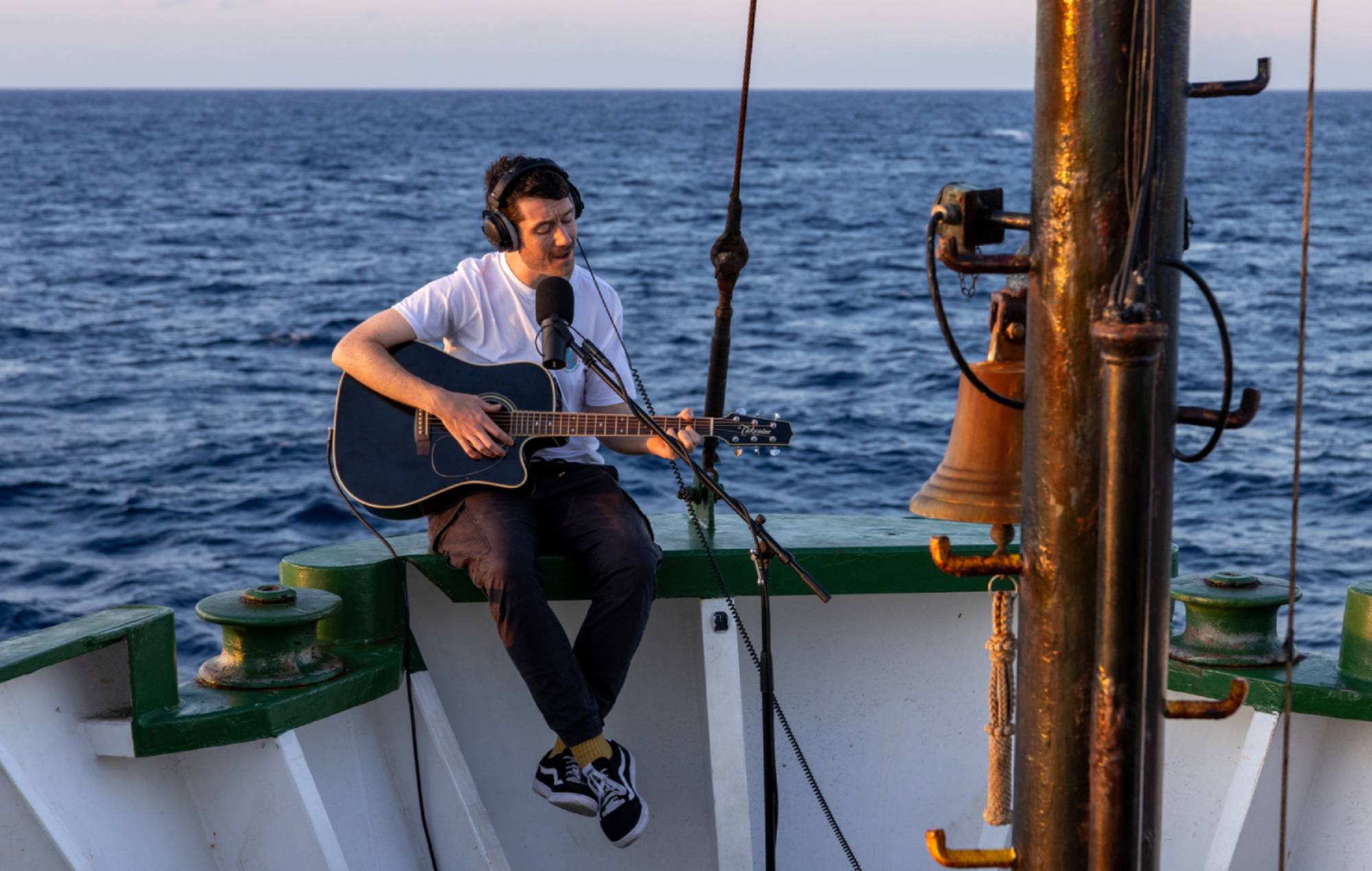 Dan Smith, Bastille jouant de la guitare à bord de l'Arctic Sunrise.  Crédit : PRESSE
