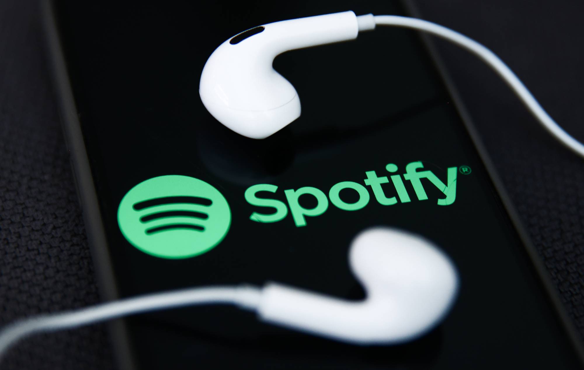 Des écouteurs et le logo Spotify affichés sur l'écran d'un téléphone sont visibles sur cette photo d'illustration prise à Cracovie, en Pologne, le 5 décembre 2023. (Photo de Jakub Porzycki/NurPhoto via Getty Images)