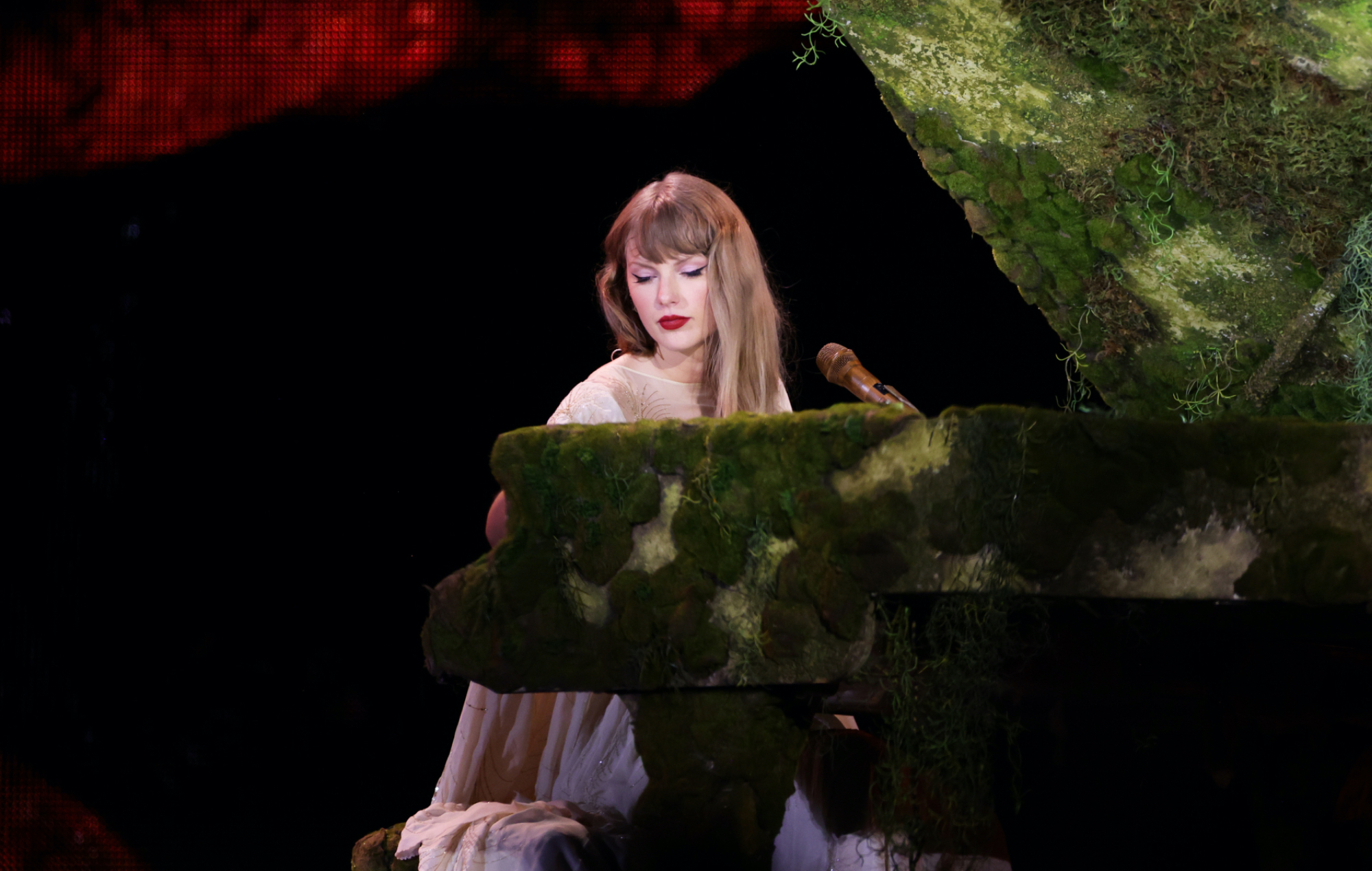 Taylor Swift joue du piano sur scène lors d'un concert de la tournée Eras Tour