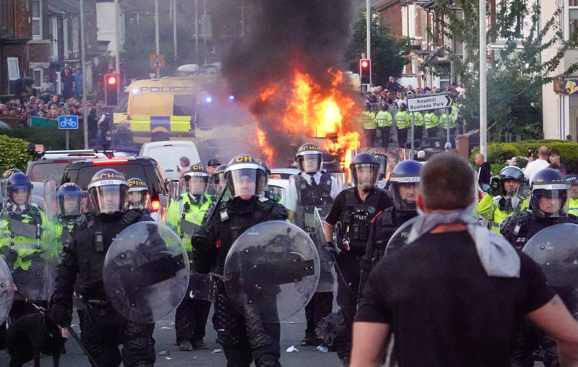 La police anti-émeute retient des manifestants près d'un véhicule de police en feu le 30 juillet 2024 à Southport, en Angleterre.