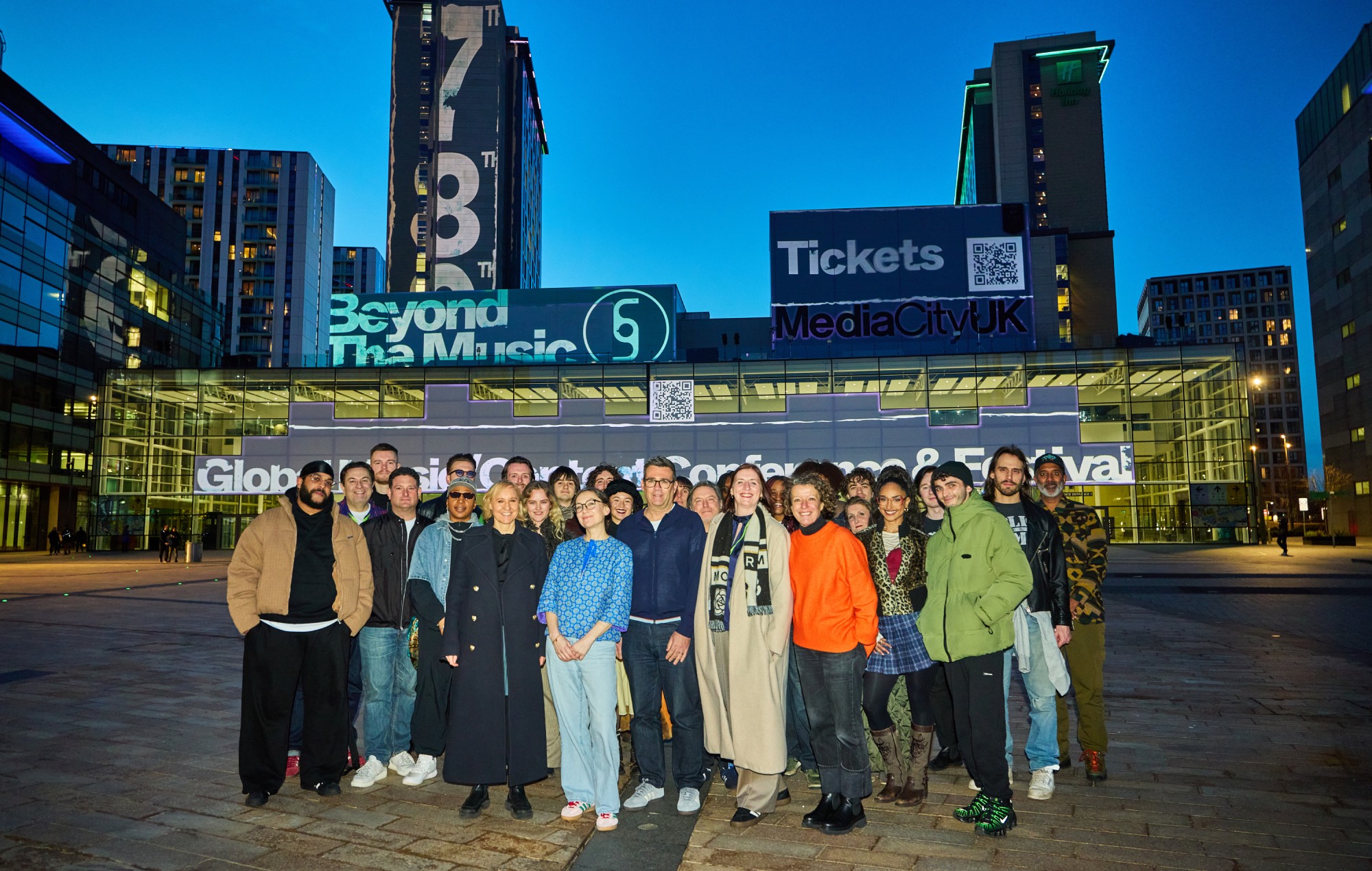 Devant LR : Sarah Pearson, Sally Cook, Andy Burnham, Rose Marley, Alice Webb et les musiciens de Manchester célèbrent le lancement de Beyond The Music à MediaCity
